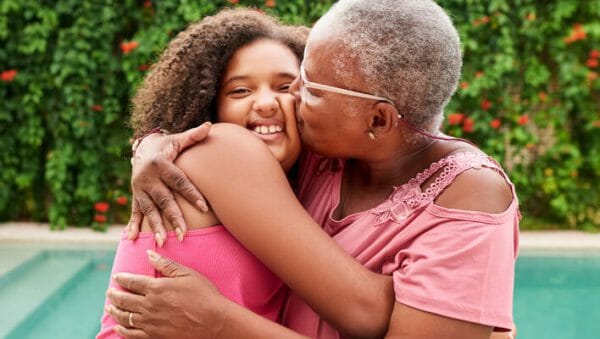 Grandmother and grandaughter outside, embracing in a warm hug