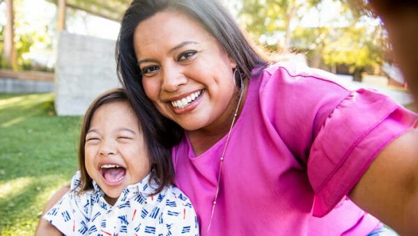 Mujer sonriente tomándose un selfie con su hija sonriente en brazos