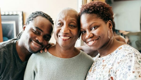 Adult siblings posing with their mature mother, smiling for the camera