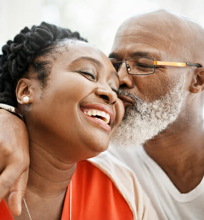 Couple smiling, man giving woman a kiss on cheek